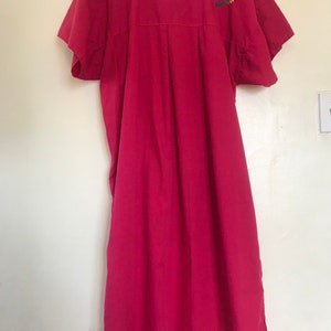 May include: A long, pink, cotton dress with short sleeves and embroidered floral details on the shoulders.