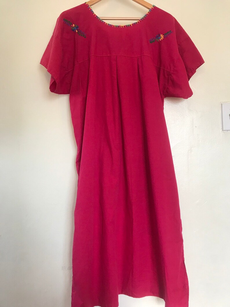 May include: A long, pink, cotton dress with short sleeves and embroidered floral details on the shoulders.