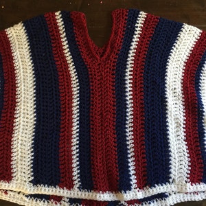 May include: A crocheted sleeveless top with red, white, and blue stripes. The top has a v-neck and a crocheted border.