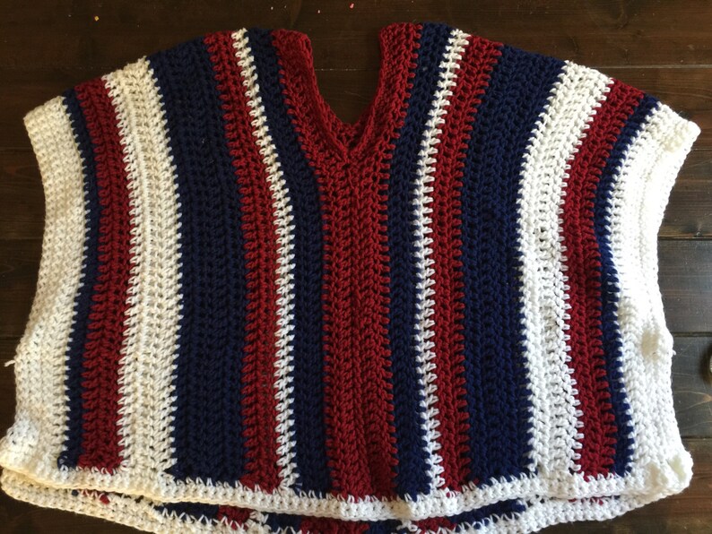 May include: A crocheted sleeveless top with red, white, and blue stripes. The top has a v-neck and a crocheted border.