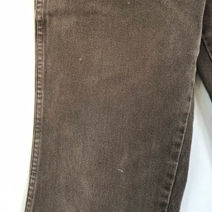 May include: Close-up of the fabric texture of a pair of brown denim jeans.
