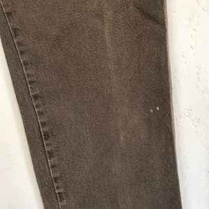 May include: Close-up of a brown pair of pants with a subtle texture. The fabric appears to be denim.