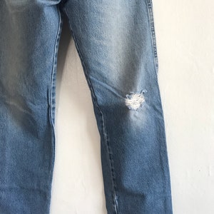 Pu&ograve; includere: Un paio di jeans in denim blu chiaro con un ginocchio consumato. I jeans hanno una gamba dritta e una vestibilit&agrave; classica.