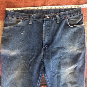 May include: A pair of blue denim jeans with a faded look. The jeans have a classic five-pocket style and a straight leg.
