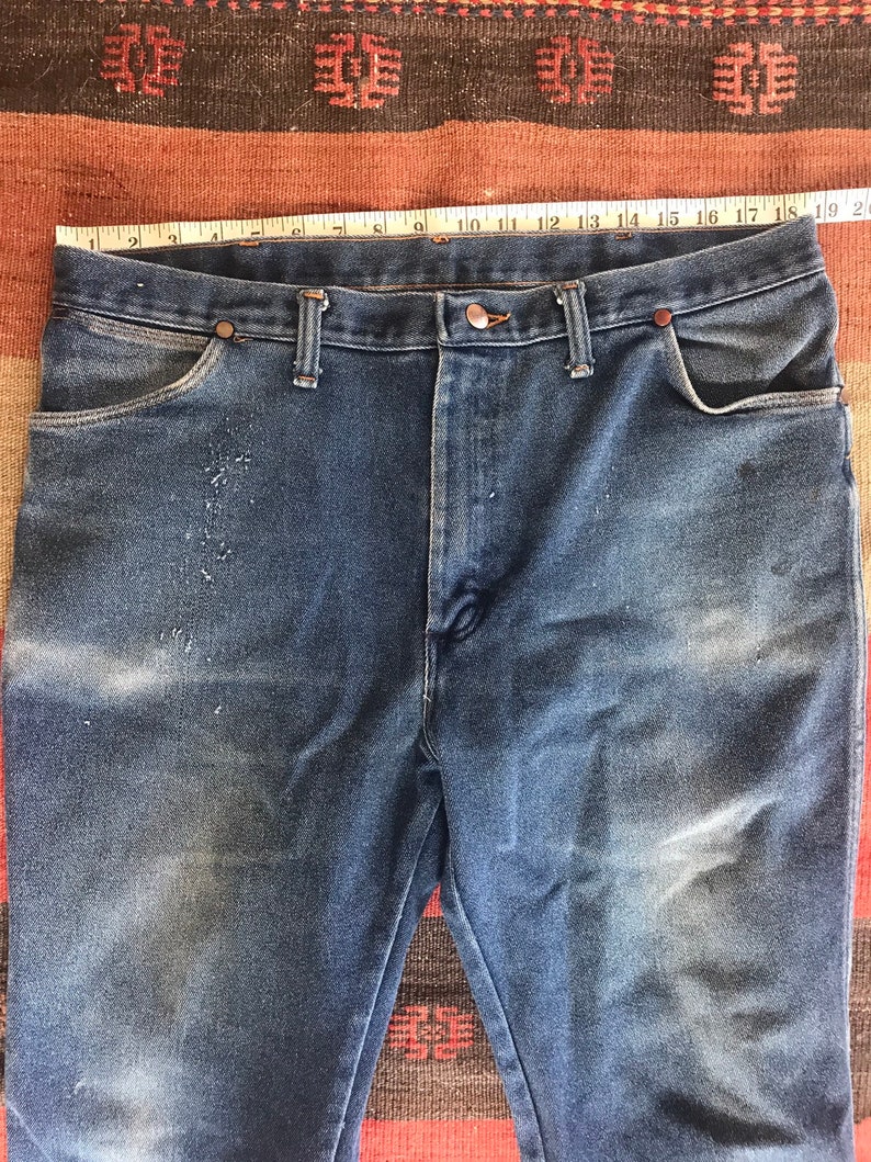 May include: A pair of blue denim jeans with a faded look. The jeans have a classic five-pocket style and a straight leg.