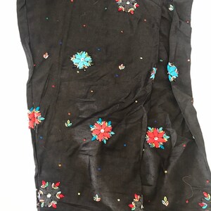 May include: Black pants with colorful embroidered flowers and sequins.