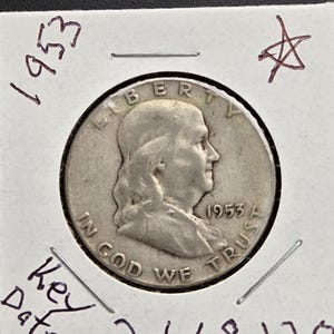 May include: A silver 1953 Franklin half dollar coin, displayed in a protective holder. The coin features a profile of Benjamin Franklin and the words "LIBERTY" and "IN GOD WE TRUST". Handwritten text on the holder reads "1953", "Key Date", and "2,668,120".