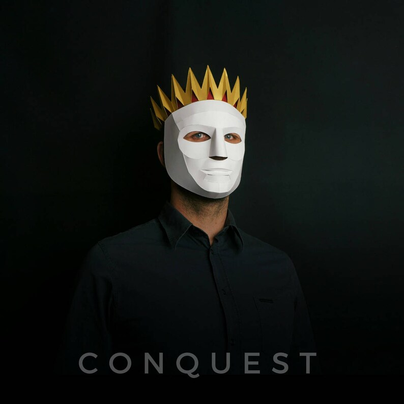 May include: A person wearing a white mask with a gold and red crown. The mask has a serious expression. The background is black. The text "CONQUEST" is printed below the image.