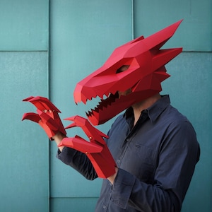 May include: A bright red, low-poly paper dragon mask and matching clawed gloves. The mask features sharp, angular geometric facets, a pointed snout, and jagged teeth. The gloves are constructed with similar red paper panels and pointed tips.