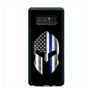 May include: Black phone case with a Spartan helmet design. The helmet is decorated with the American flag and a blue thin line.