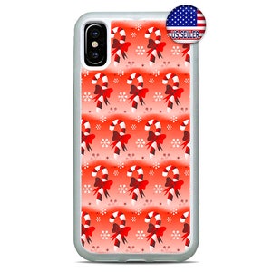 Pode incluir: Uma capa de telefone branca e vermelha com um padrão repetido de bengalas doces com laços vermelhos e flocos de neve em um fundo gradiente vermelho. A capa tem uma borda branca.