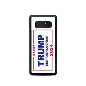 May include: A black phone case with a white background and a red, white, and blue sticker that says "TRUMP KEEP AMERICA GREAT! 2024" with five red stars.