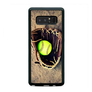 May include: A black phone case with a brown leather baseball glove and a yellow softball. The glove is open and the ball is resting inside.