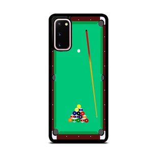 May include: A green felt pool table with a brown wooden frame and a black phone case. The phone case has a camera lens cutout and a white cue ball on the table. There is a red and yellow pool cue on the table.