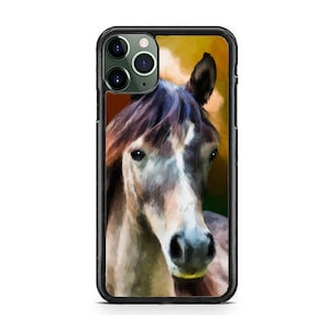 May include: A black phone case with a close-up image of a brown and white horse's head. The horse has a white stripe down its face and a brown mane. The background is a blurred image of a field.