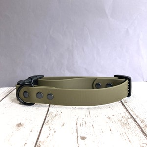 May include: A green rubber dog collar with a black buckle and metal D-ring. The collar has three black metal rivets.