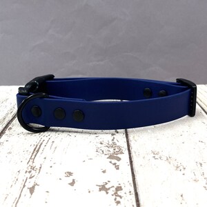 May include: A dark blue silicone dog collar with a black buckle and D-ring. The collar has three black dots on the front.
