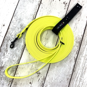 May include: A coiled bright yellow dog lead with a black clip and a black handle. The handle features the text "DITSY PET." The lead is made of a flexible, durable material and is shown on a wooden surface.