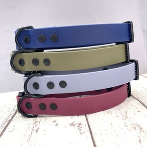 May include: Four dog collars stacked on top of each other. The collars are made of a soft, flexible material and have a black buckle and black metal accents. The collars are in the colours blue, green, light blue, and burgundy.