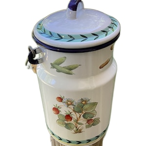 May include: White enamel canister with a blue rim and a green and white floral design. The canister has a lid with a blue handle and a green and white floral design.