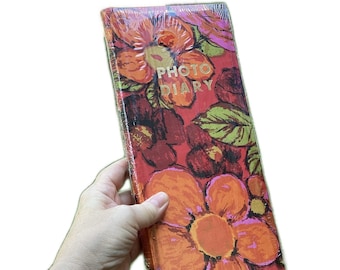 May include: A red, orange, and green photo diary with a floral pattern and the words "PHOTO DIARY" in gold lettering.