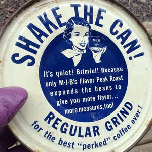 May include: Vintage tin can label for MJB coffee. It features a woman holding a can of coffee and the text "Shake the Can!" and "Regular Grind for the best "perked" coffee ever!"