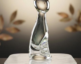 May include: A vintage, hand-blown glass cat sculpture. The clear glass cat has a sleek, minimalist design with a curved body and head. It sits on a marble base. A small card reads "VINTAGE HAND-BLOWN GLASS CAT - COLLECTOR'S ITEM."