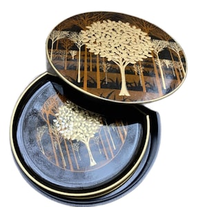 Peut inclure: Ensemble de quatre sous-verres noirs avec une bordure dorée et un motif d'arbre doré et brun. Les sous-verres sont dans une boîte ronde noire avec une bordure dorée et un motif d'arbre assorti.