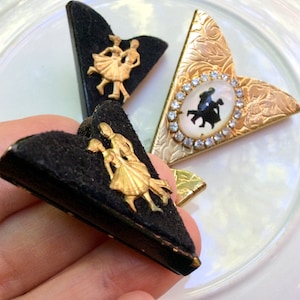 May include: Three vintage brooches featuring a dancing couple. The brooches are made of gold-tone metal and have a black velvet backing. One brooch has a clear rhinestone encrusted frame around the couple.