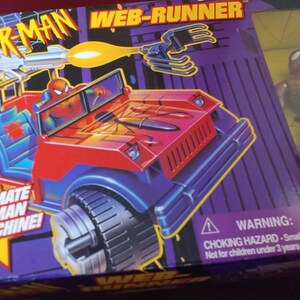 May include: A red and blue toy vehicle with a Spider-Man figure in the driver's seat. The vehicle has a web-shooter and grappling claws. The box says "The Ultimate Spider-Man Battle Machine!" and "Web-Runner".