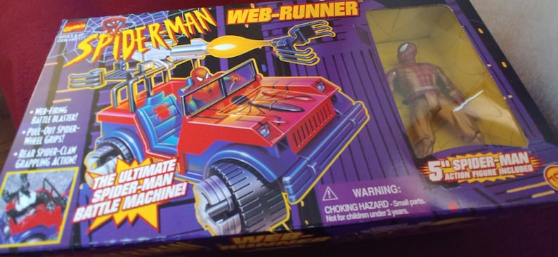 May include: A red and blue toy vehicle with a Spider-Man figure in the driver's seat. The vehicle has a web-shooter and grappling claws. The box says "The Ultimate Spider-Man Battle Machine!" and "Web-Runner".