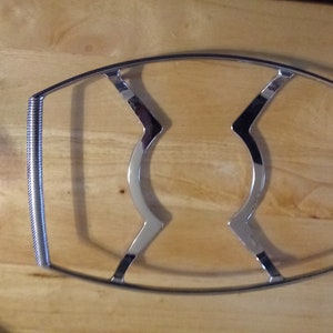 May include: A silver metal cooling rack with a curved design. The rack is made of wire and has a smooth finish.