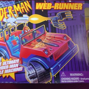 May include: A red and blue toy vehicle with a Spider-Man figure in the driver's seat. The vehicle has a web-firing battle blaster, pull-out spider-wheel grips, and rear spider-claw grappling action. The box also includes a 5-inch Spider-Man action figure. The text on the box reads "SPIDER-MAN WEB-RUNNER" and "THE ULTIMATE SPIDER-MAN BATTLE MACHINE!"