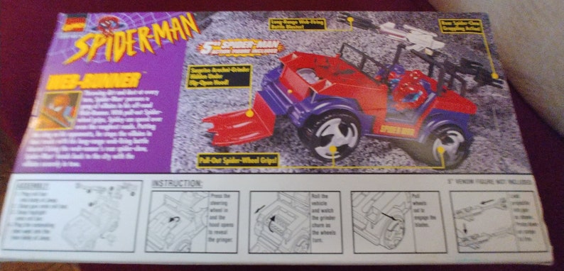 May include: A red and blue Spider-Man toy jeep with a pull-out spider-wheel grip. The box features instructions for playing with the toy. The text on the box reads "Spider-Man Web-Slinger".