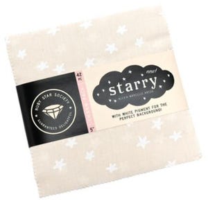May include: A stack of fabric squares with a cream background and white star pattern. A black band with the text "Ruby Star Society" and "Guaranteed Delightful" wraps around the squares. The label reads "starry" and "with white pigment for the perfect background".