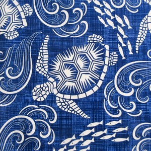 May include: A blue and white fabric with a repeating pattern of stylized sea turtles and waves. The turtles are white with a black outline and the waves are white on a blue background.