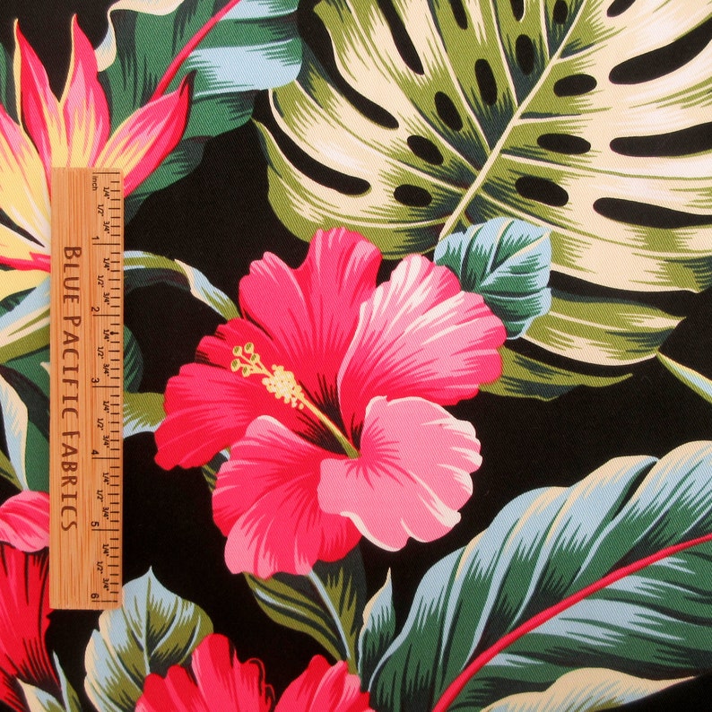Puede incluir: Una tela negra con estampado tropical que presenta flores de hibisco rosas y hojas verdes. La tela se mide con una regla que dice "Blue Pacific Fabrics".