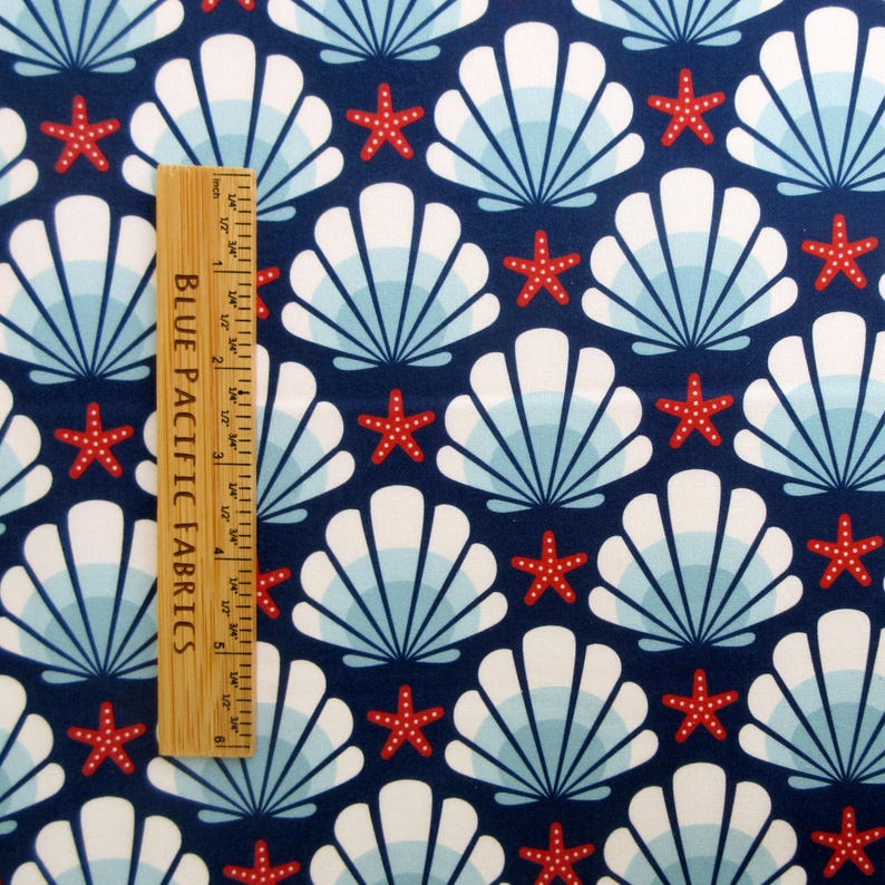 May include: Navy blue fabric with a repeating pattern of white seashells and red starfish. The fabric has a subtle blue and white ombre effect in the seashells.