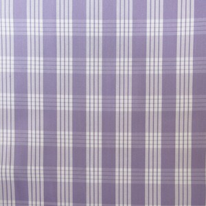 May include: A close-up of a fabric with a plaid pattern. The fabric features a light purple background with a grid of white and light purple lines. The lines intersect to create a classic plaid design, suitable for various textile applications.