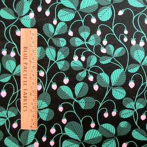 May include: A fabric with a repeating pattern of stylized strawberries and leaves in shades of teal, gray-green, and pink on a black background. A wooden ruler with the text "BLUE PACIFIC FABRICS" is on the left side.