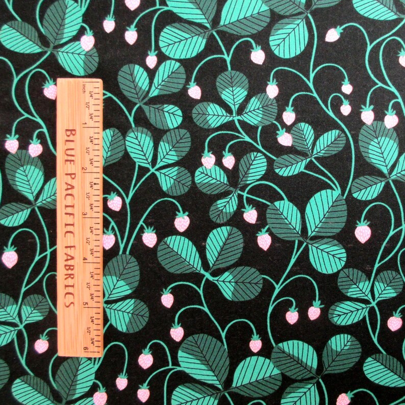 May include: A fabric with a repeating pattern of stylized strawberries and leaves in shades of teal, gray-green, and pink on a black background. A wooden ruler with the text "BLUE PACIFIC FABRICS" is on the left side.