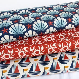 May include: Three fabric swatches with nautical themes. The top swatch is navy blue with white seashells and red starfish. The middle swatch is red with white crab silhouettes. The bottom swatch is white with blue and red sailboats.