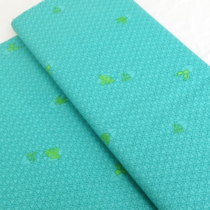 May include: Teal fabric with a geometric pattern of small triangles and a repeating design of green stylized plants.