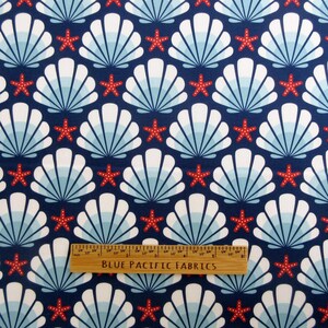 May include: A navy blue fabric with a repeating pattern of white seashells and red starfish. A wooden ruler with the text "BLUE PACIFIC FABRICS" is placed on the fabric.
