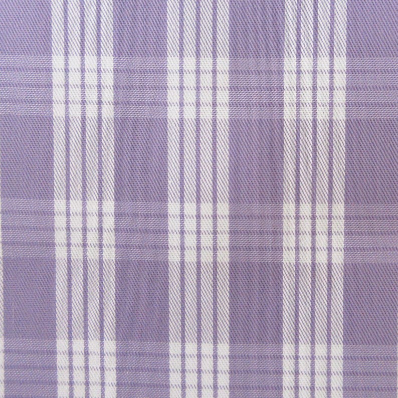 May include: Close-up of a fabric with a plaid pattern. The fabric features a light purple background with a grid of white vertical and horizontal lines. The lines create a classic plaid design, suitable for various textile applications.