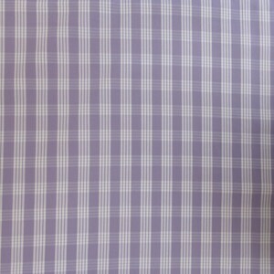 May include: A close-up of a fabric with a lilac background and a white plaid pattern. The plaid consists of vertical and horizontal lines, creating a grid-like design. The fabric appears to be smooth and possibly used for clothing or home decor.