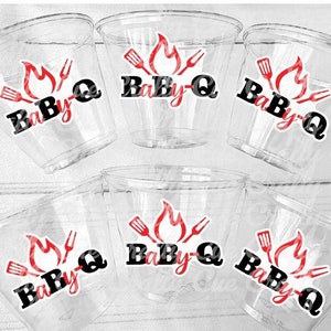 Op de afbeelding: Zes doorzichtige plastic bekers met rode en zwarte vinyl stickers waarop "BaBy-Q" staat met een vlam en grillgereedschap ontwerp.