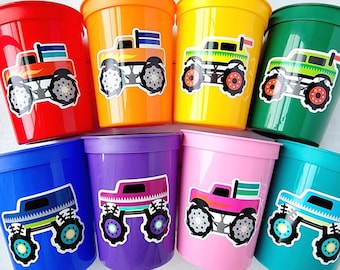 Puede incluir: Ocho vasos de plástico con diseños de monster trucks. Los vasos son de diferentes colores: rojo, naranja, amarillo, verde, azul, morado, rosa y turquesa. Cada vaso tiene un monster truck de color diferente con una bandera en la parte superior.