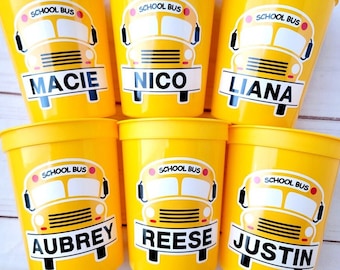 Peut inclure: Six gobelets en plastique jaunes avec des motifs de bus scolaires et les noms "Macie", "Nico", "Liana", "Aubrey", "Reese" et "Justin" imprimés dessus.