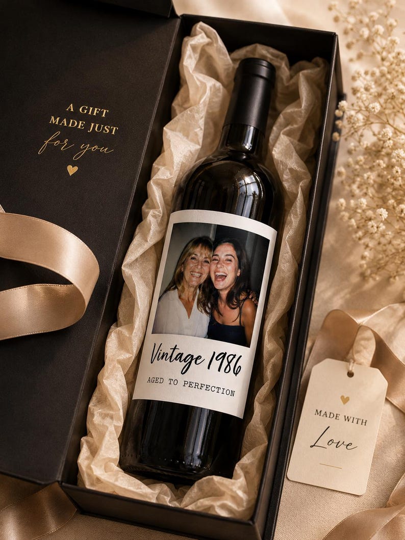 May include: A black gift box containing a dark glass wine bottle with a custom photo label featuring two people. The label reads Vintage 1986 AGED TO PERFECTION. The box interior has gold text A GIFT MADE JUST for you and a tag reading MADE WITH Love.